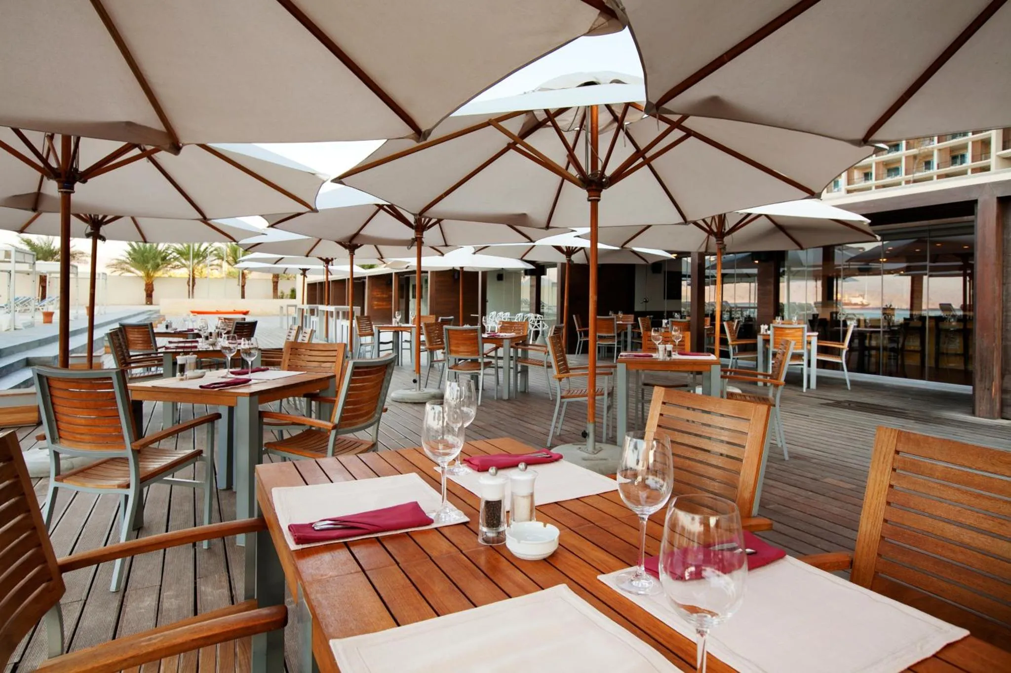 Tables dressées sur une terrasse ombragée avec vue sur la mer.