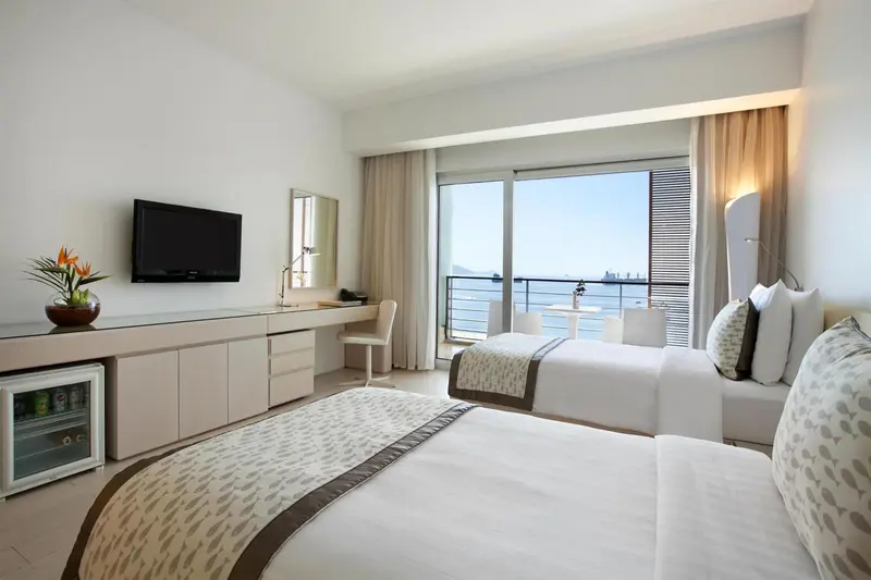 Une chambre lumineuse avec deux lits et une vue sur la mer.