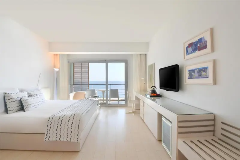 Chambre lumineuse avec un grand lit donnant sur la mer.