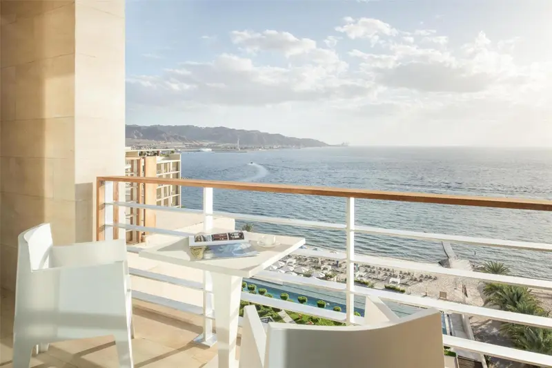 Vue d'une terrasse avec mobilier blanc donnant sur la mer et le littoral.