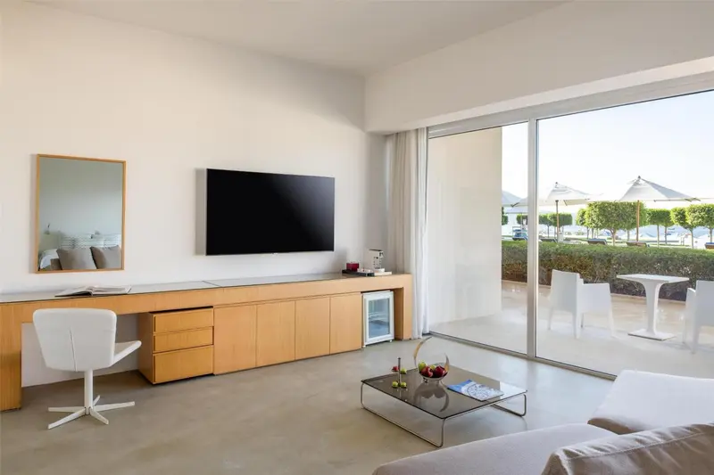 Un salon lumineux s'ouvre sur une terrasse avec mobilier blanc.