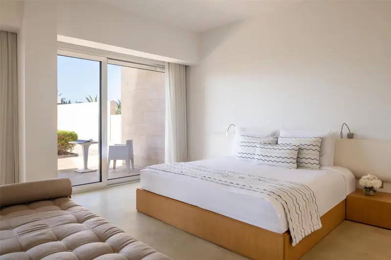 Une chambre lumineuse avec un grand lit et un coin salon.