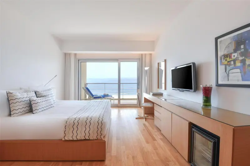 Une chambre lumineuse avec un grand lit donnant sur la mer.