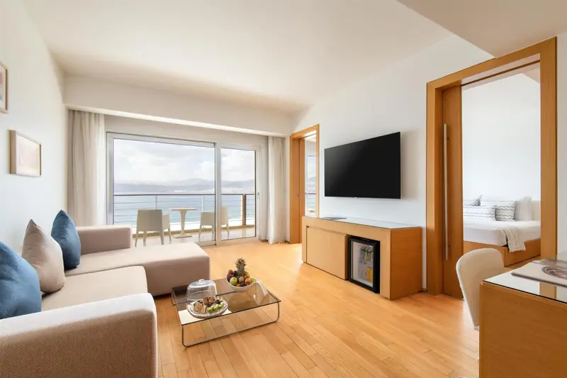 Espace de séjour lumineux avec canapé et vue sur la mer.