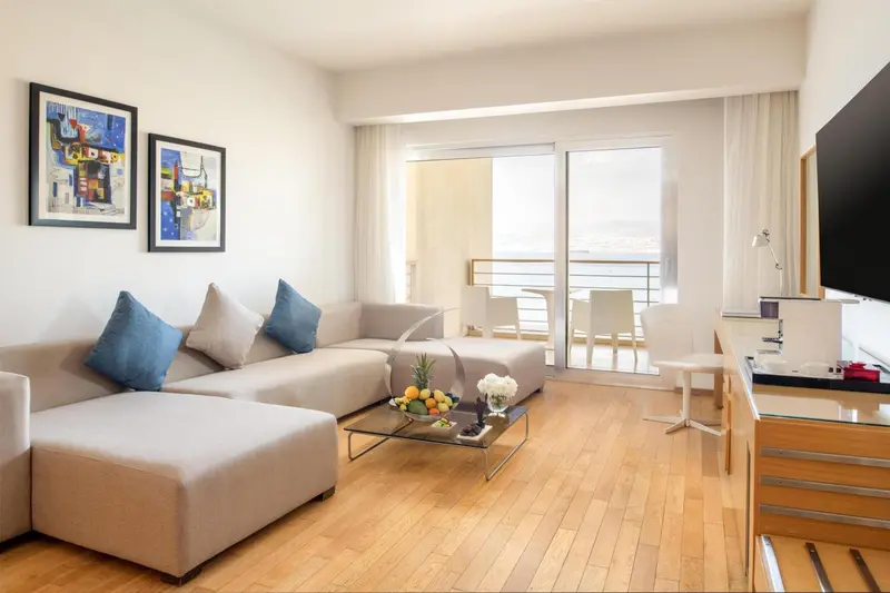 Espace de détente lumineux avec canapé, table basse et accès à une terrasse.