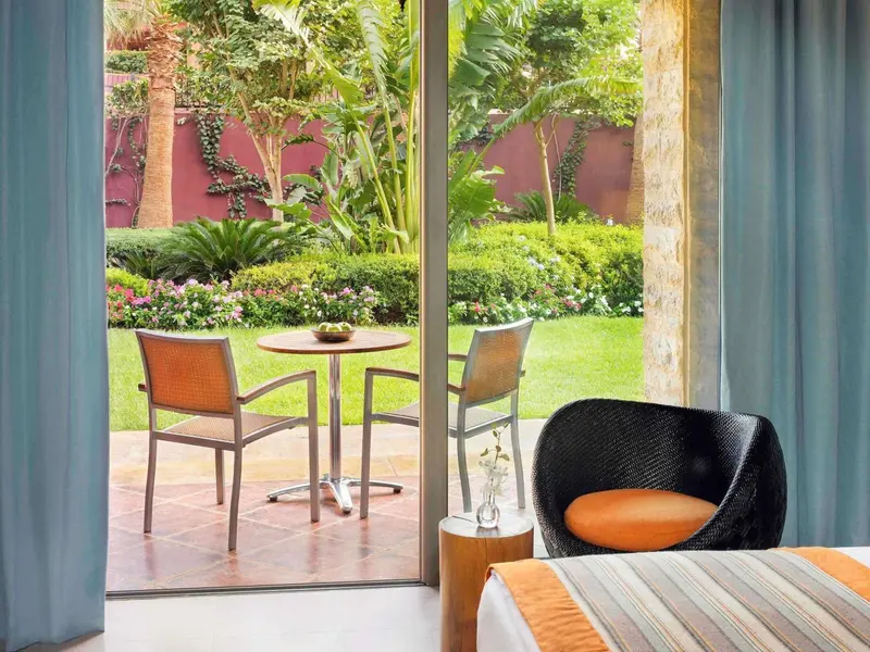 Une terrasse avec une table et des chaises donne sur un jardin verdoyant.
