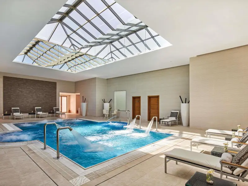 Une piscine intérieure lumineuse avec des chaises longues.