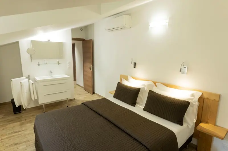 Une chambre lumineuse avec un grand lit et un espace lavabo.