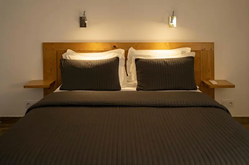 Un lit double avec une tête de lit en bois et des oreillers blancs.