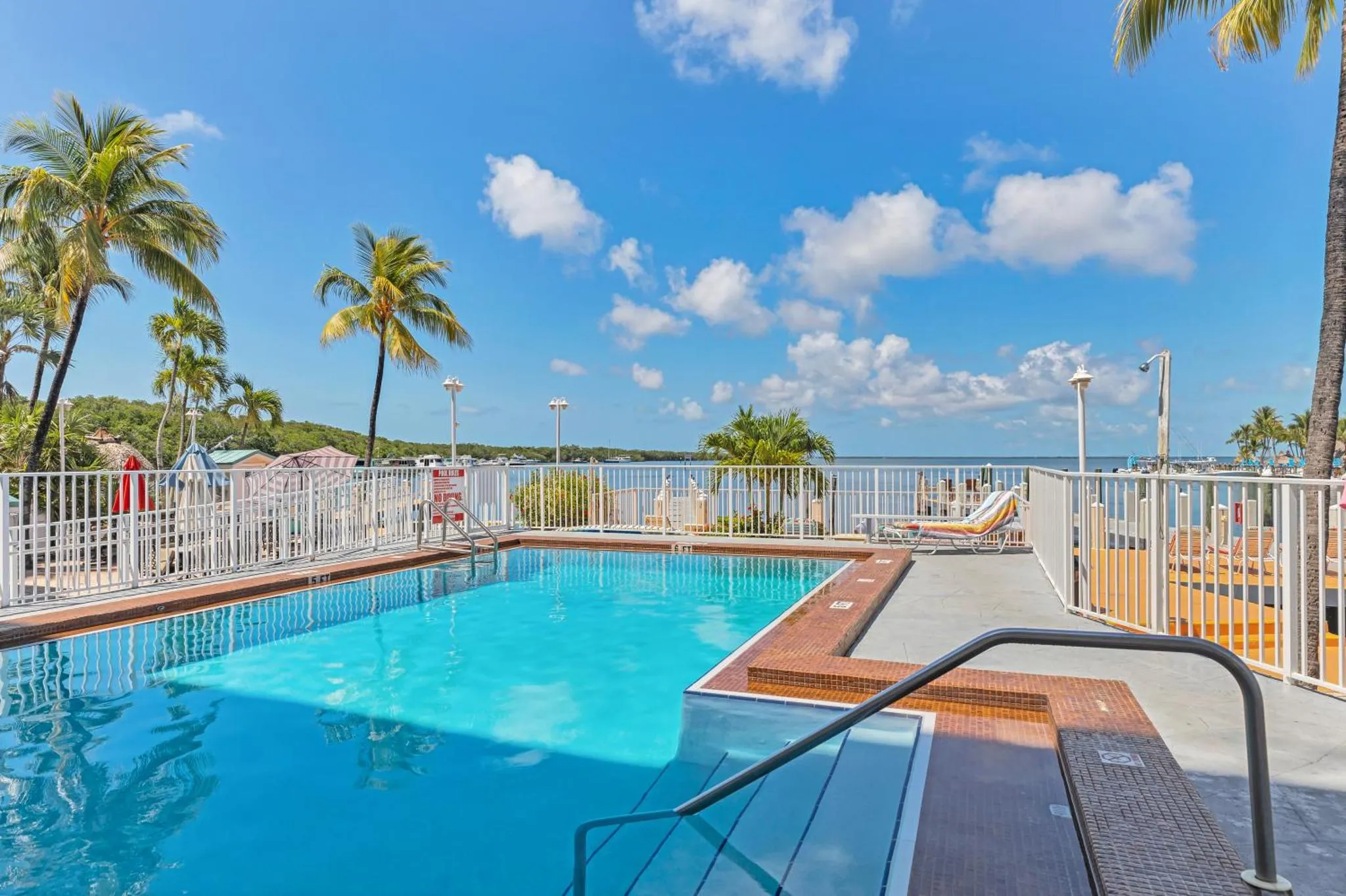 Une piscine turquoise bordée d'une terrasse ensoleillée avec des transats.