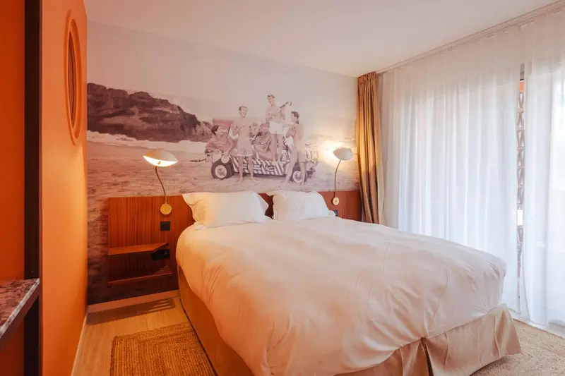 Une chambre lumineuse avec un grand lit et un mur décoré d'une fresque marine.