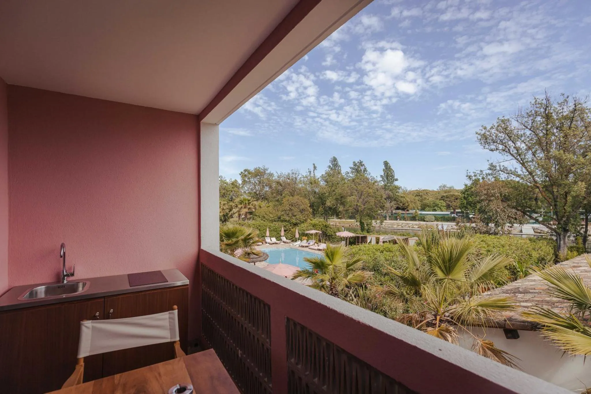 Une terrasse avec un évier et une table donne sur une piscine et une végétation luxuriante.