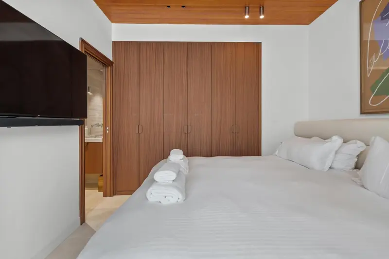 Une chambre lumineuse avec un grand lit recouvert d'une couette blanche et de serviettes enroulées.