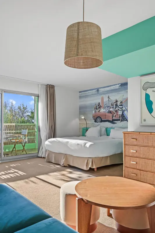 Une chambre lumineuse avec un lit et une décoration murale sur le thème du surf.