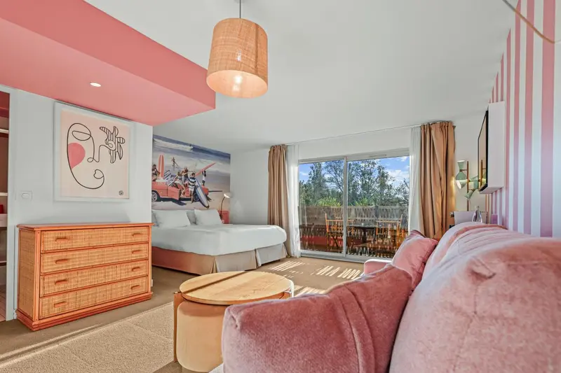 Une chambre lumineuse avec un canapé rose et un lit blanc.