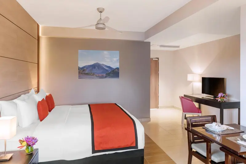 Une chambre lumineuse avec un grand lit et un coin repas.