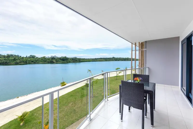 Terrasse avec mobilier d'extérieur donnant sur une plage et une étendue d'eau.