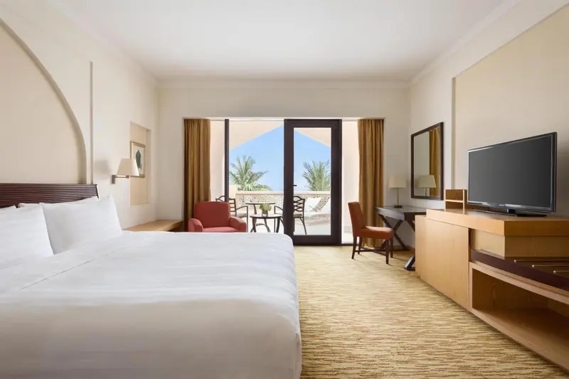Chambre lumineuse avec un grand lit et une vue sur la mer par de larges baies vitrées.