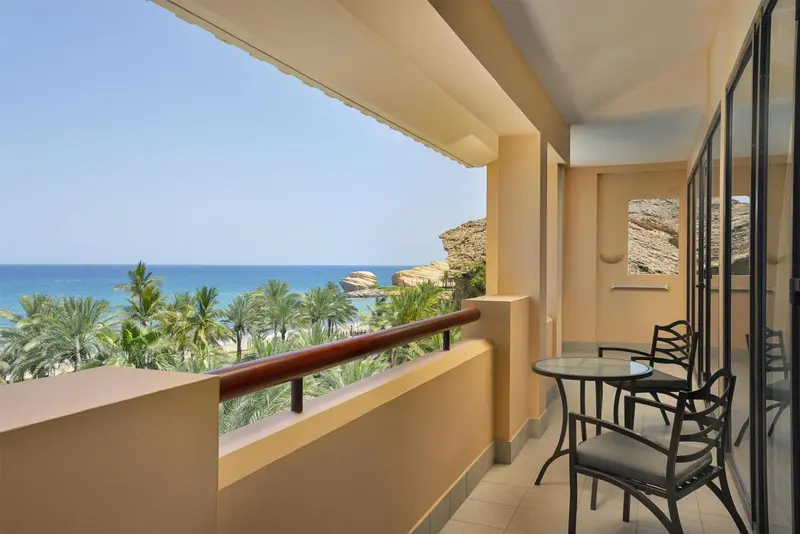 Terrasse avec mobilier d'extérieur donnant sur une vue mer et végétation.