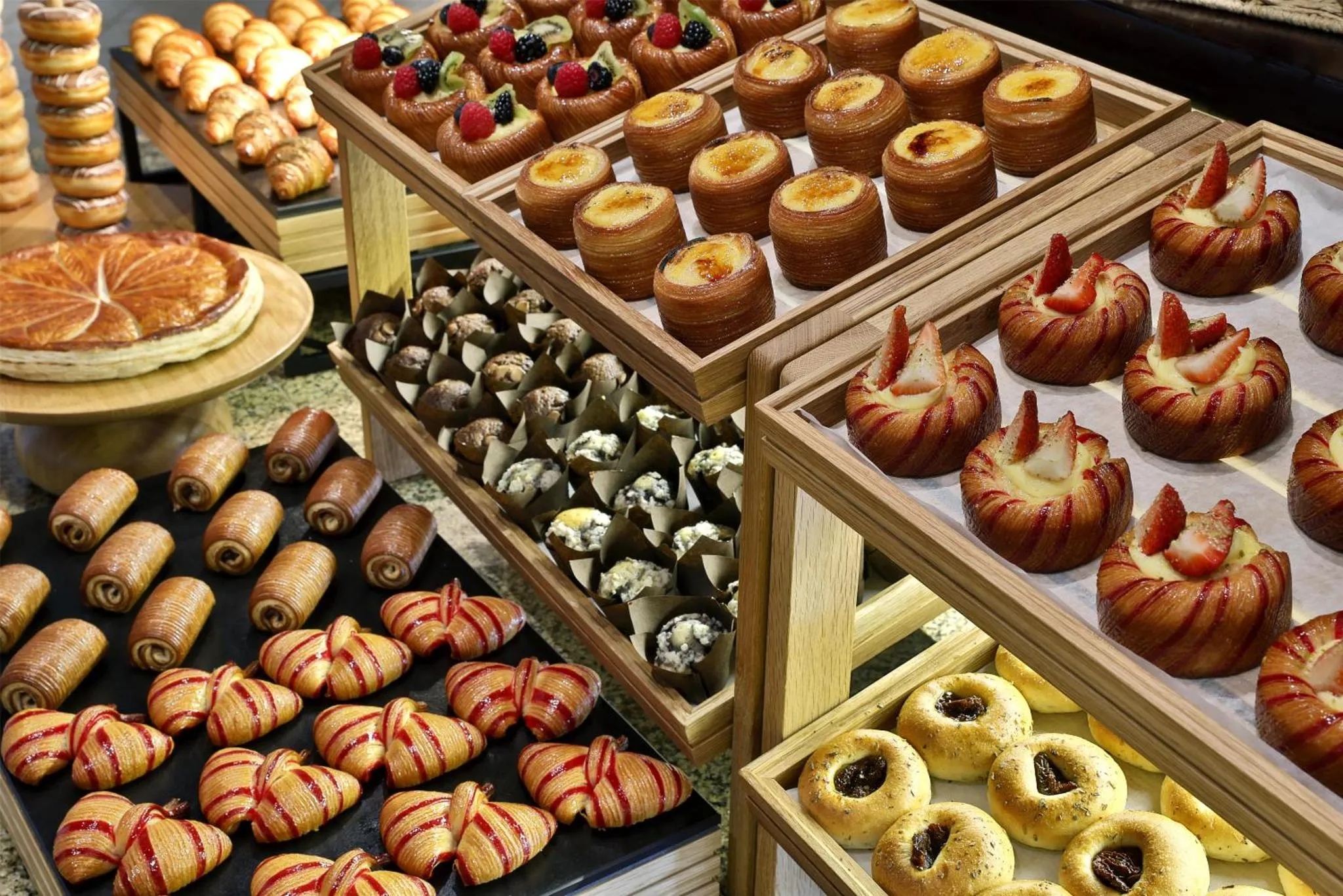 Présentation de pâtisseries variées sur des présentoirs en bois.