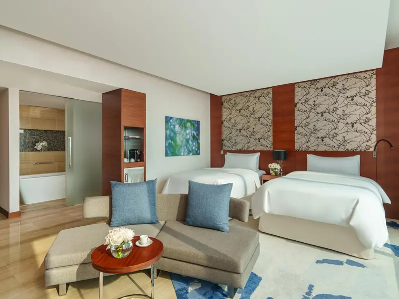 Une chambre lumineuse avec deux lits simples et un coin salon.