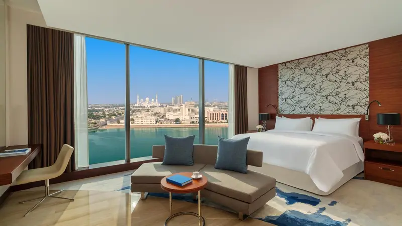 Chambre lumineuse avec un grand lit et une vue sur la mer.