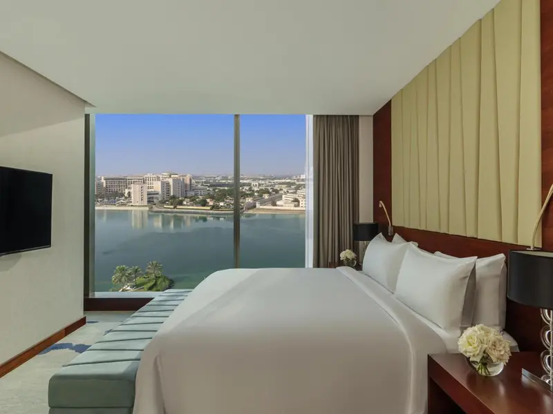 Chambre lumineuse avec un grand lit et vue sur la mer.