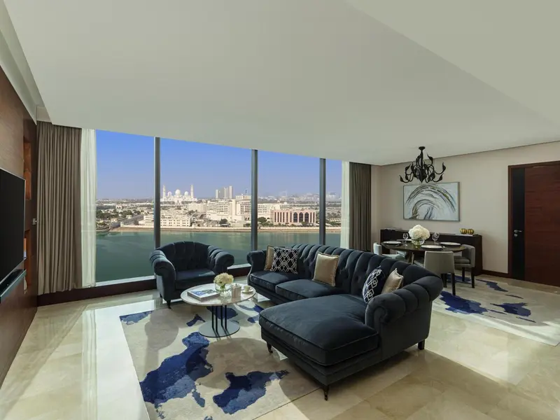 Un salon spacieux avec canapés et table basse offre une vue sur la mer et la ville.