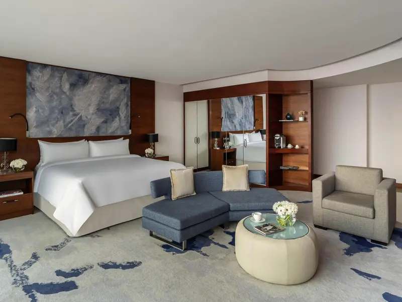 Chambre lumineuse avec un grand lit et un coin salon confortable.