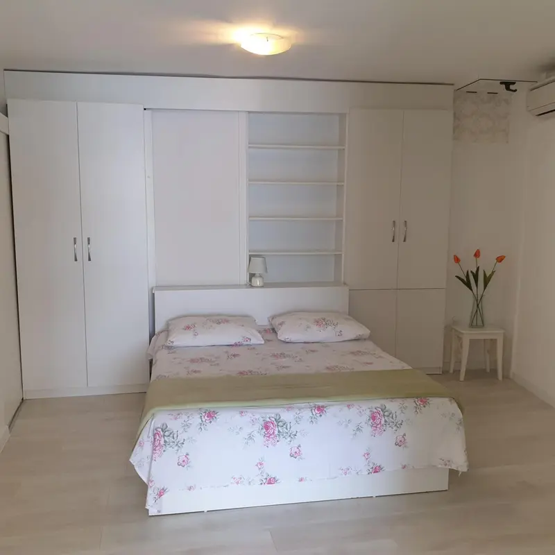 Une chambre lumineuse avec un lit recouvert d'une couette fleurie et de grands placards blancs.