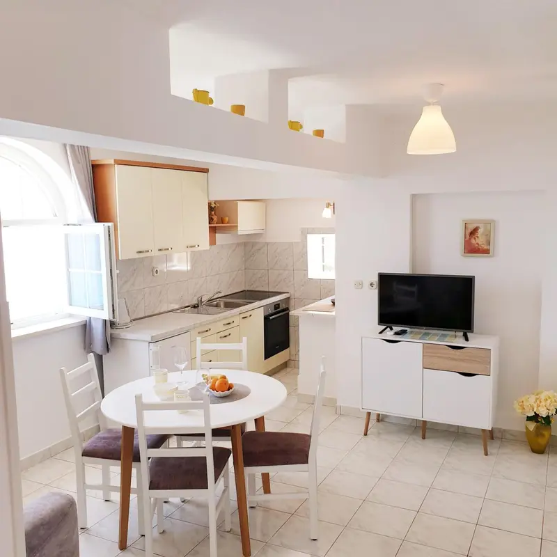 Une cuisine lumineuse s'ouvre sur un coin repas avec une table ronde.