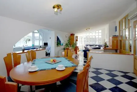 Une table ronde est mise avec des assiettes et des fruits dans une pièce lumineuse.