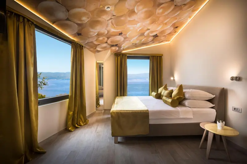 Chambre lumineuse avec un lit double et vue sur la mer.