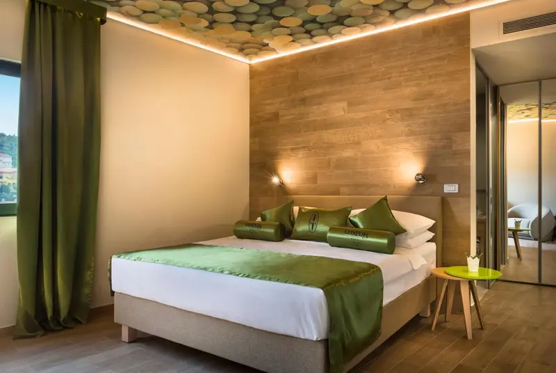 Une chambre d'hotel avec un lit recouvert d'une couette blanche et de coussins verts.