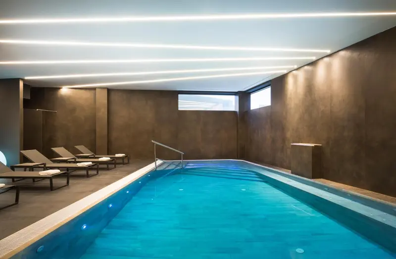 Une piscine intérieure avec des chaises longues sur le bord.