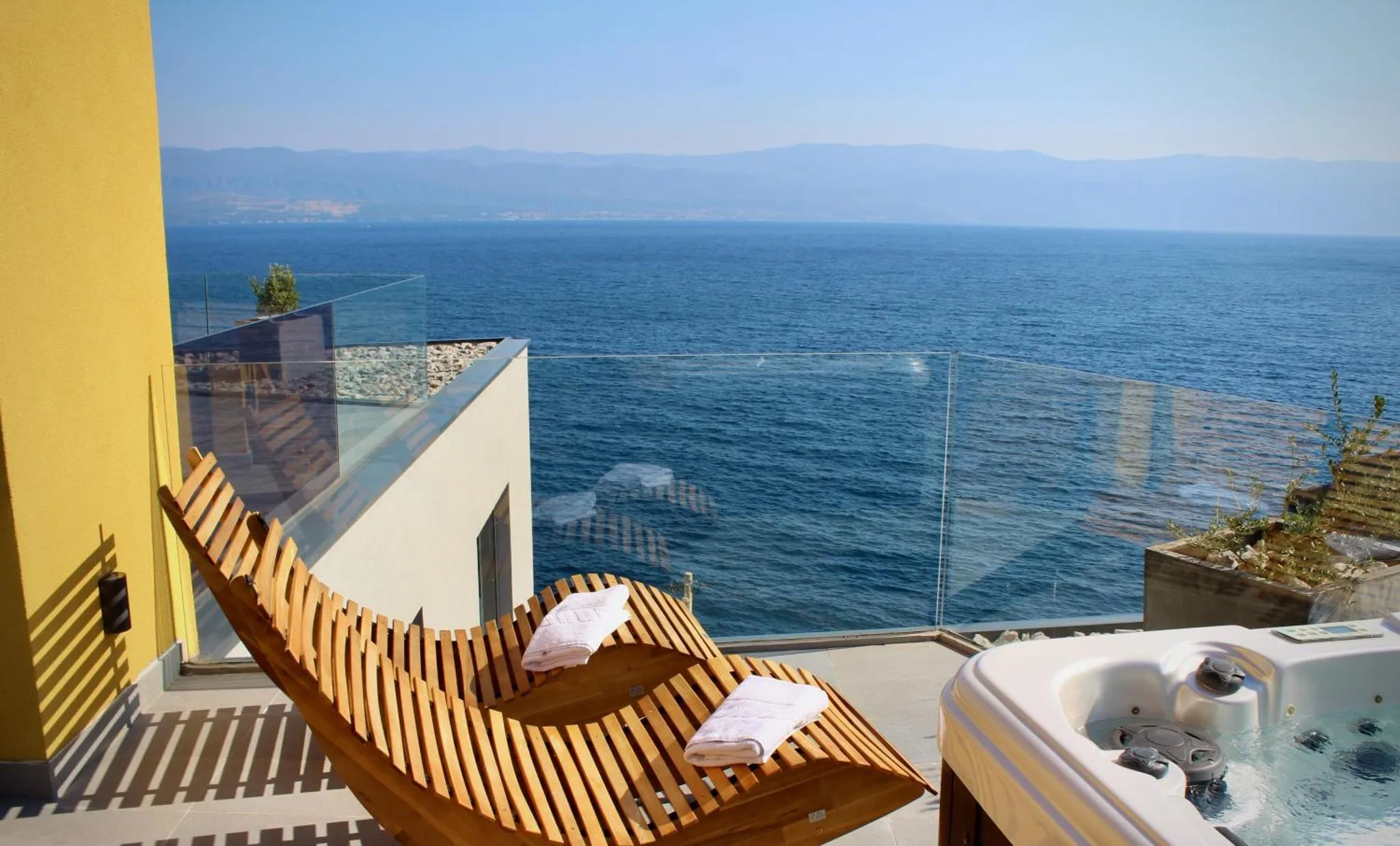Un transat en bois se trouve sur une terrasse avec vue sur la mer.