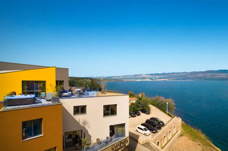 Vue aérienne d'un bâtiment moderne surplombant la mer et les montagnes.