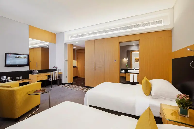 Une chambre lumineuse avec deux lits simples et un coin salon.