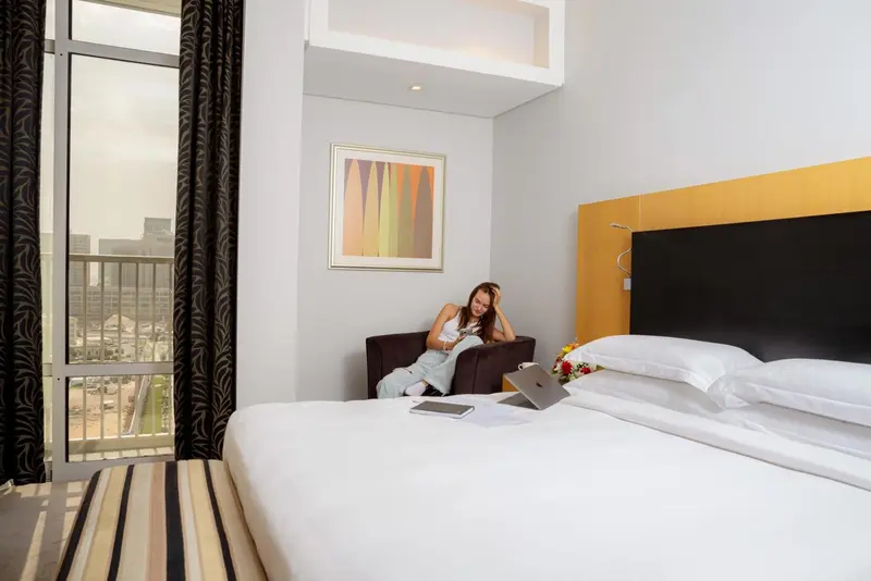 Une personne assise sur un fauteuil dans une chambre d'hôtel lumineuse.