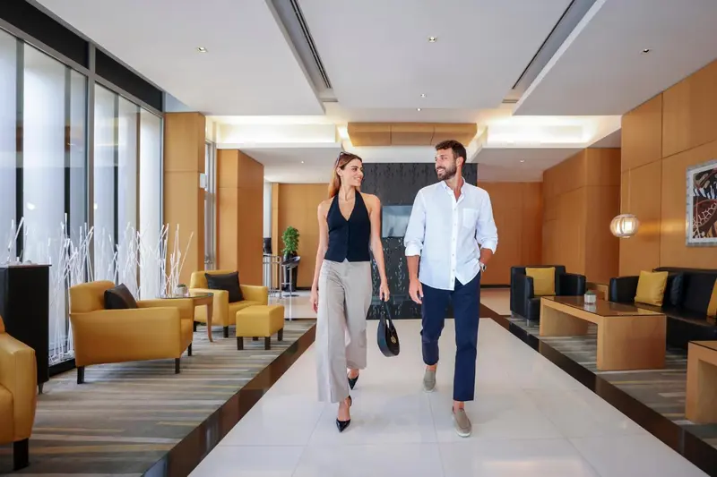 Un couple marche dans un hall d'accueil lumineux et moderne.