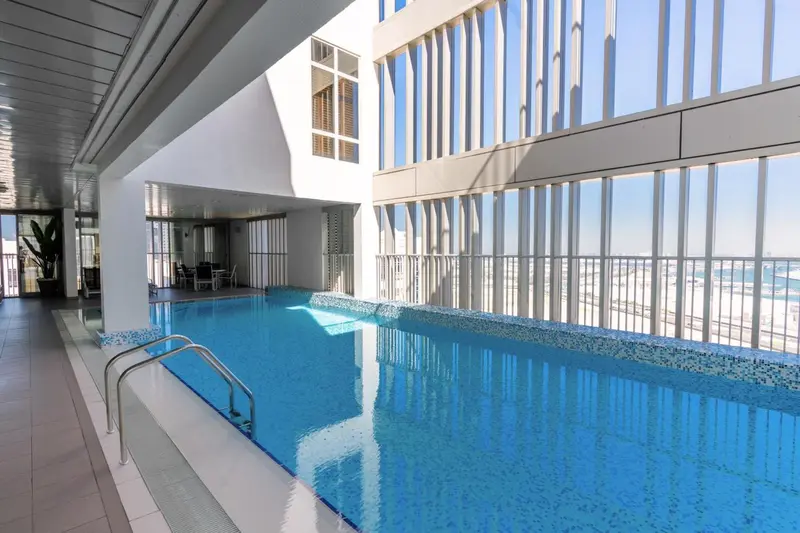 Une piscine intérieure lumineuse avec une vue sur la ville.