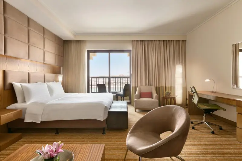 Chambre lumineuse avec un grand lit et un espace détente.