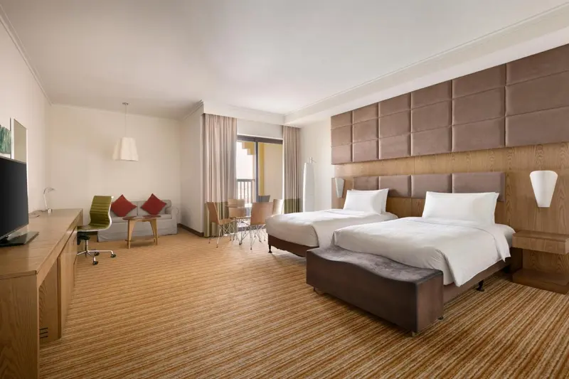 Une chambre lumineuse avec deux lits simples et un coin salon.