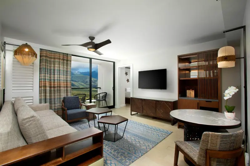 Espace de vie intérieur avec canapé, table basse et vue sur un paysage verdoyant.