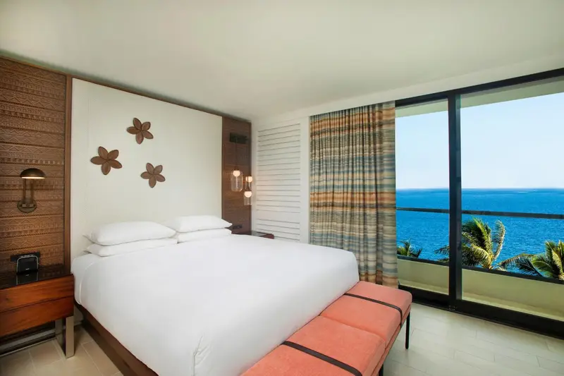 Une chambre lumineuse avec un grand lit et vue sur la mer.