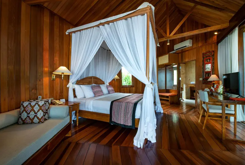 Une chambre lumineuse avec un grand lit à baldaquin en bois.
