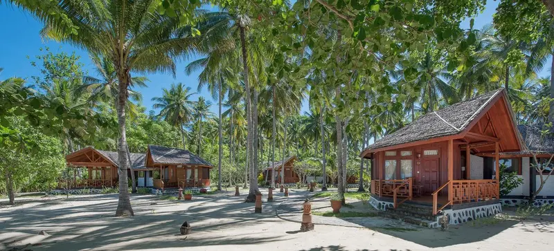 Cabanes en bois au milieu d'une végétation tropicale luxuriante.