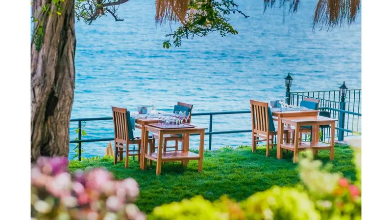Tables de restaurant en terrasse avec vue sur la mer.