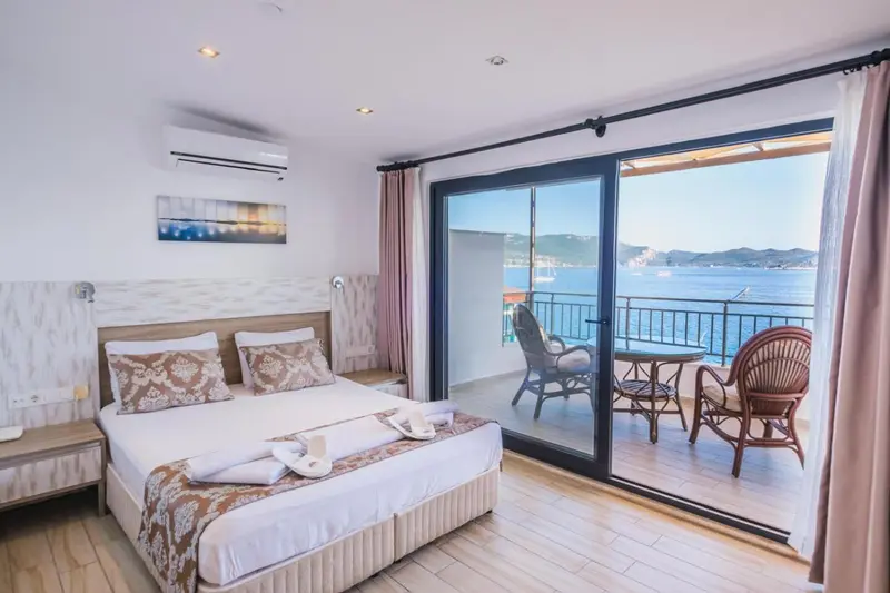 Une chambre lumineuse s'ouvre sur une terrasse avec vue sur la mer.