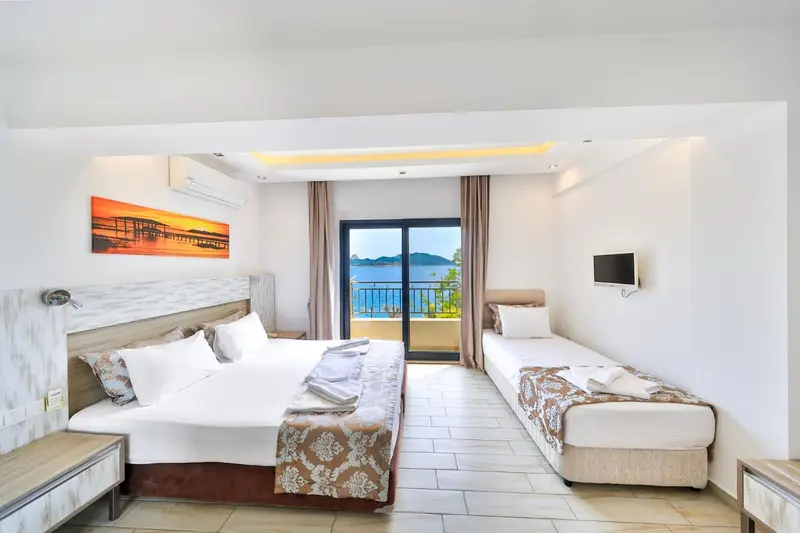 Une chambre lumineuse avec un grand lit et un lit simple, donnant sur une vue mer.
